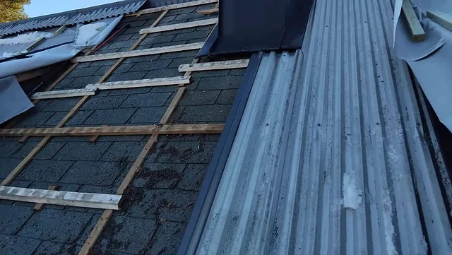 Tak i rehabilitering med delvis demontert taktekking og synlig pipe.